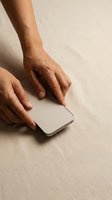 Woman hands touching smartphone screen on beige surface with natural lighting and shadows for technology and communication concepts.
