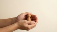 Two cupped hands in protective gesture against neutral beige background, symbolizing care, support and security for design projects.