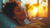 Young African American woman relaxing with eyes closed, enjoying peaceful moment at sunset with warm golden light streaming through window.