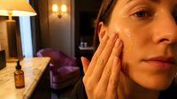 Young woman applying facial cream in modern bathroom during evening skincare routine for healthy glowing skin and anti-aging beauty treatment at home.