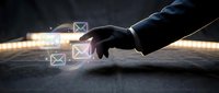 Businessman hand touching digital envelope icons floating above surface, representing email communication and digital messaging technology for business correspondence.