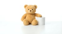 Adorable brown teddy bear sitting next to white mug on clean surface, perfect for children's products, nursery decor, and cozy lifestyle designs.