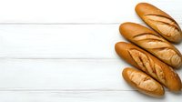 Fresh crusty baguettes arranged on white wooden background with copy space. Traditional French bread loaves showing golden brown crust and texture.