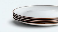 Stack of minimalist white ceramic dinner plates with copper metallic rim detail on light background, modern tableware design for contemporary dining.