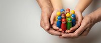 Hands holding colorful wooden balls in cupped palms against neutral background. Concept of diversity, teamwork, unity and inclusion in community.