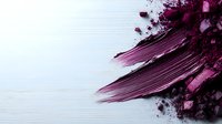 Purple cosmetic powder and lipstick smear on white wooden background. Makeup artist workspace with crushed eyeshadow and beauty products for fashion design.