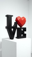 Modern LOVE sculpture with bold black letters and a red geometric polygonal heart on a white pedestal in a minimalist gallery setting.
