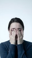 Young woman covering face with hands expressing stress, anxiety, depression, mental health struggles, emotional pain, burnout or overwhelming feelings.