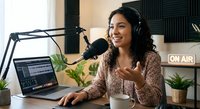 Young Hispanic woman podcaster recording show in professional studio with microphone, laptop and headphones for broadcasting content creation.