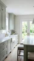 Bright kitchen interior with sage green cabinetry, white subway tile backsplash, farmhouse sink, and French doors opening to garden. Ideal for home design, renovation, and interior styling projects.