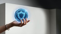 Cropped hand holding glowing blue shield symbol representing cybersecurity, data protection, and digital safety for technology and business concepts.