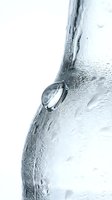 Close-up of a single water droplet clinging to a frosted glass surface with condensation and ice crystals, isolated on white background for design use.