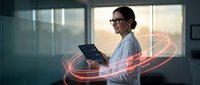 Professional businesswoman using digital tablet with glowing data streams in modern office environment for technology and innovation concepts.