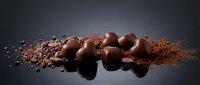 Chocolate truffles and cocoa powder arranged on dark surface with scattered crumbs, suitable for food photography, culinary blogs, and confectionery marketing materials.