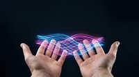 Open hands presenting glowing blue and pink energy waves flowing between palms against dark background for technology and innovation concepts.
