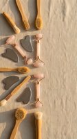 Natural skincare tools collection with bamboo brushes and rose quartz gua sha stones arranged on linen background for spa wellness routine.