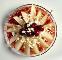 Fresh pear and cranberry smoothie bowl topped with crumbled feta cheese and arranged in decorative pattern, photographed from above on white surface.