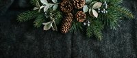 Festive evergreen arrangement with pinecones, dried botanicals and faux berries on dark textured surface, ideal for holiday greeting cards and seasonal marketing materials.