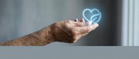 Senior man's hand holding glowing heart symbol, representing love, care, charity, and compassion in healthcare and wellness concepts.