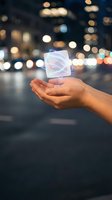 Hand holding glowing geometric cube with bokeh city lights background. Futuristic technology concept for innovation, digital transformation, and business solutions.