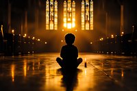 Silhouette of person sitting in meditation pose on church floor with golden sunlight streaming through stained glass windows, creating mystical atmosphere.