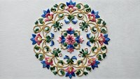Intricate floral mandala embroidery with colorful blooms and ornate scrollwork on white fabric background for decorative textile and craft projects.
