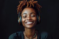 Young African American woman with dreadlocks enjoying music through headphones, smiling with eyes closed against dark background.