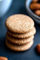 Stack of fresh almond macarons with delicate crispy texture on dark background, selective focus on top cookie, macro food photography for bakery marketing.