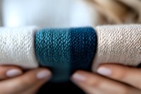 Close-up macro shot of knitted fabric texture in teal blue and white colors showing detailed wool or cotton yarn pattern with selective focus effect.