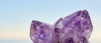 Two large purple amethyst crystal formations with natural faceted surfaces against soft gradient background for healing and spiritual wellness concepts.