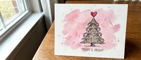 Merry and bright greeting card with watercolor pink splashes, decorated evergreen tree, and red heart on white background.