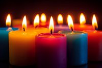 Colorful burning candles with glowing flames against dark background, creating warm ambiance for meditation, celebration, or romantic setting.
