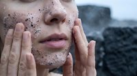 Young woman applying natural exfoliating face scrub with coffee grounds for skincare routine and spa treatment at home.