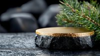 Natural stone product display platform with gold metallic top surface and pine branch decoration on dark background with selective focus and copy space.