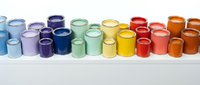 Colorful ceramic mugs and cups arranged in rainbow spectrum on white surface, perfect for kitchen decor, beverage service, and hospitality design projects.