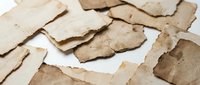 Aged torn paper fragments scattered on white background creating vintage texture for scrapbooking and craft projects with weathered brown edges.