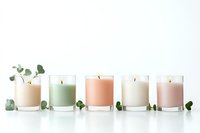 Aromatic scented candles in glass holders with pastel wax colors and fresh eucalyptus leaves arranged in minimalist style on white background.
