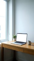 Modern home office workspace with open laptop displaying blank white screen on wooden desk near window for remote work and productivity applications.