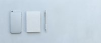 Modern white smartphone, notebook and pen arranged in minimalist flat lay composition on clean background for business and technology concepts.