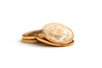 Stack of shiny gold coins on white background with selective focus and shallow depth of field, showing wealth and financial concept.