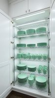 Organized kitchen pantry cabinet with mint green dishware stacked on chrome wire shelves, illuminated by LED strip lighting for elegant storage.