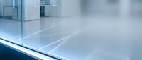 Modern glass office building interior with clean transparent surfaces and soft natural lighting creating professional corporate atmosphere.