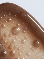 Brown cosmetic serum with bubbles and water droplets on neutral background for skincare and beauty product advertising campaigns.