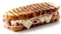 Grilled sandwich with melted Swiss cheese and thinly sliced ham on toasted sourdough bread, featuring distinctive grill marks and oozing cheese, photographed on white background.