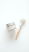 Skincare face mask jar with wooden brush on white background for beauty routine and spa treatment applications.