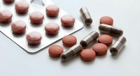 Various pharmaceutical pills and capsules in blister packs and loose on white surface for medical treatment and healthcare concepts.