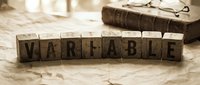 Wooden letter blocks spelling VARIABLE on rustic table with vintage book and eyeglasses in warm natural lighting for business and education concepts.