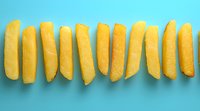 Fresh yellow lemon wedges arranged in row pattern on bright turquoise background, minimalist food composition for healthy lifestyle and citrus concepts.