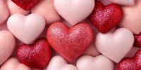 Sparkling red and pink glittery hearts scattered together creating romantic Valentine's Day love celebration background for greeting cards and decorations.