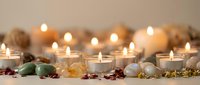 Warm candlelight creates peaceful spa atmosphere with natural stones, dried flowers and soft glowing flames for relaxation and wellness meditation.
